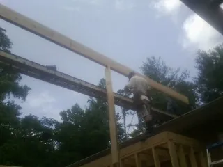 Carpenter setting a ridge beam over a new addition frame — Ice Dam Removal by Roofing Brothers in Devon