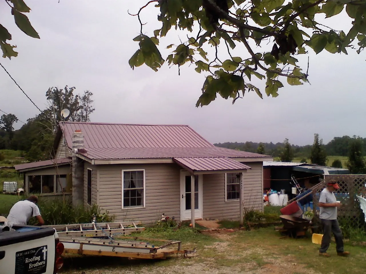 Crew finishing a mauve metal roof on a small farmhouse in Devon